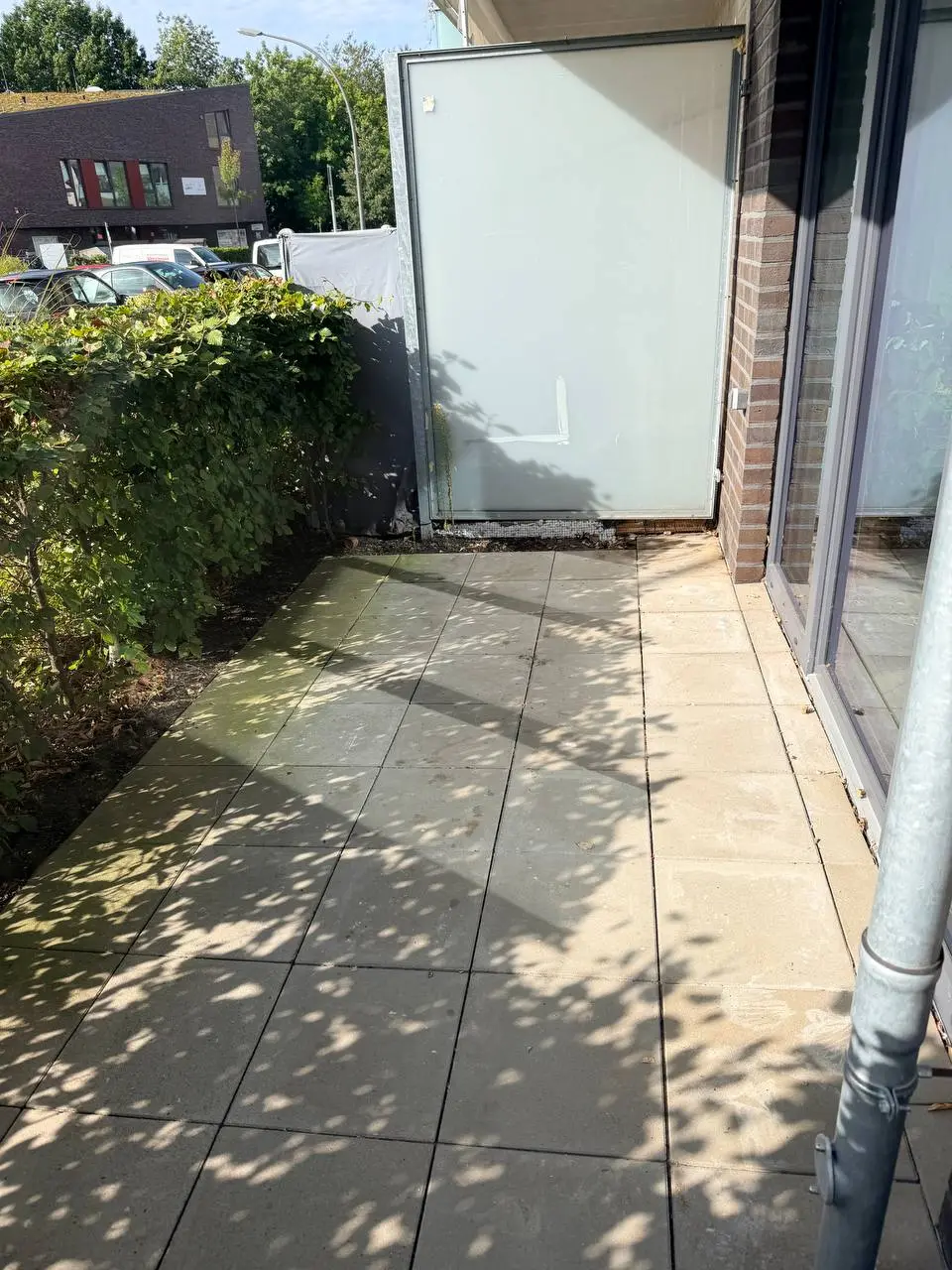 Dieselbe Terrasse in Hamburg-Eppendorf nach der Abholung, leere Betonplatten vor dem Glas-Sichtschutz