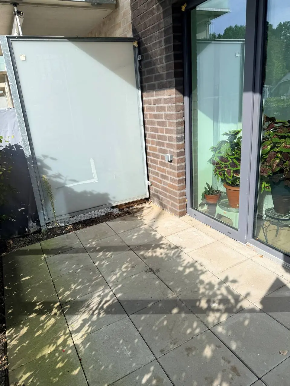 Leere Terrasse in Eppendorf mit geöffnetem Glas-Sichtschutz und Blick auf die Terrassentür