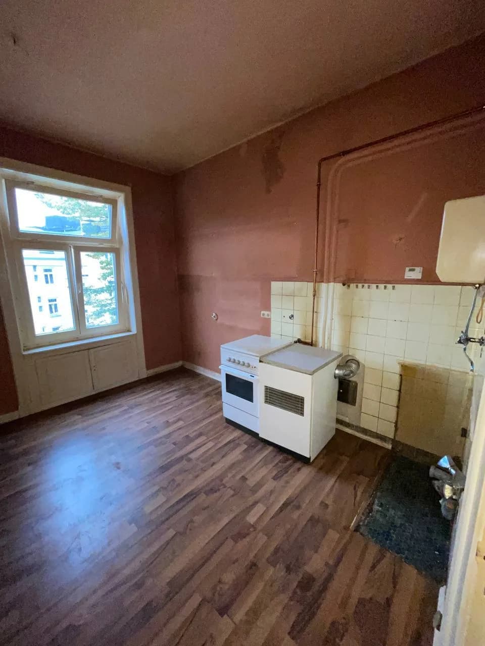 Küche am Eppendorfer Weg nach dem Abbau der Einbauküche mit Wandfliesen, Leitungen und Rundbogen-Altbaufenster