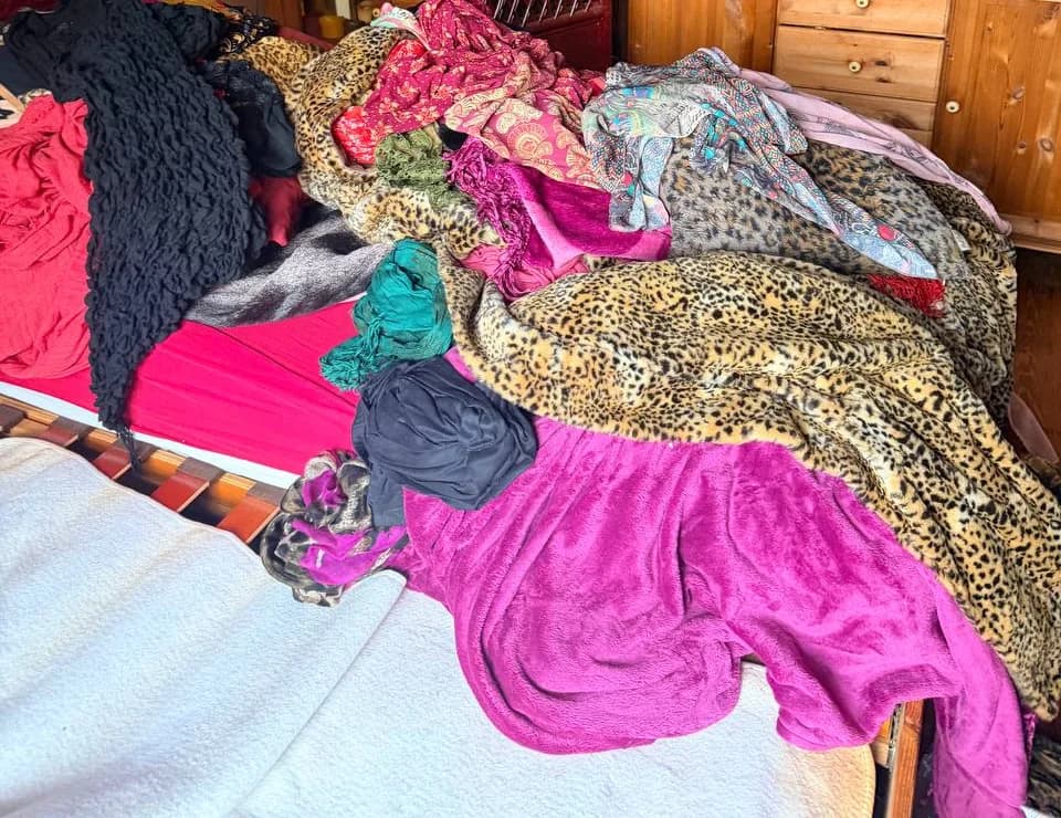 Bett mit einem Berg aus Kleidern, Decken im Leopardenmuster und Tüchern in einer Wohnung am Eppendorfer Weg vor der Räumung