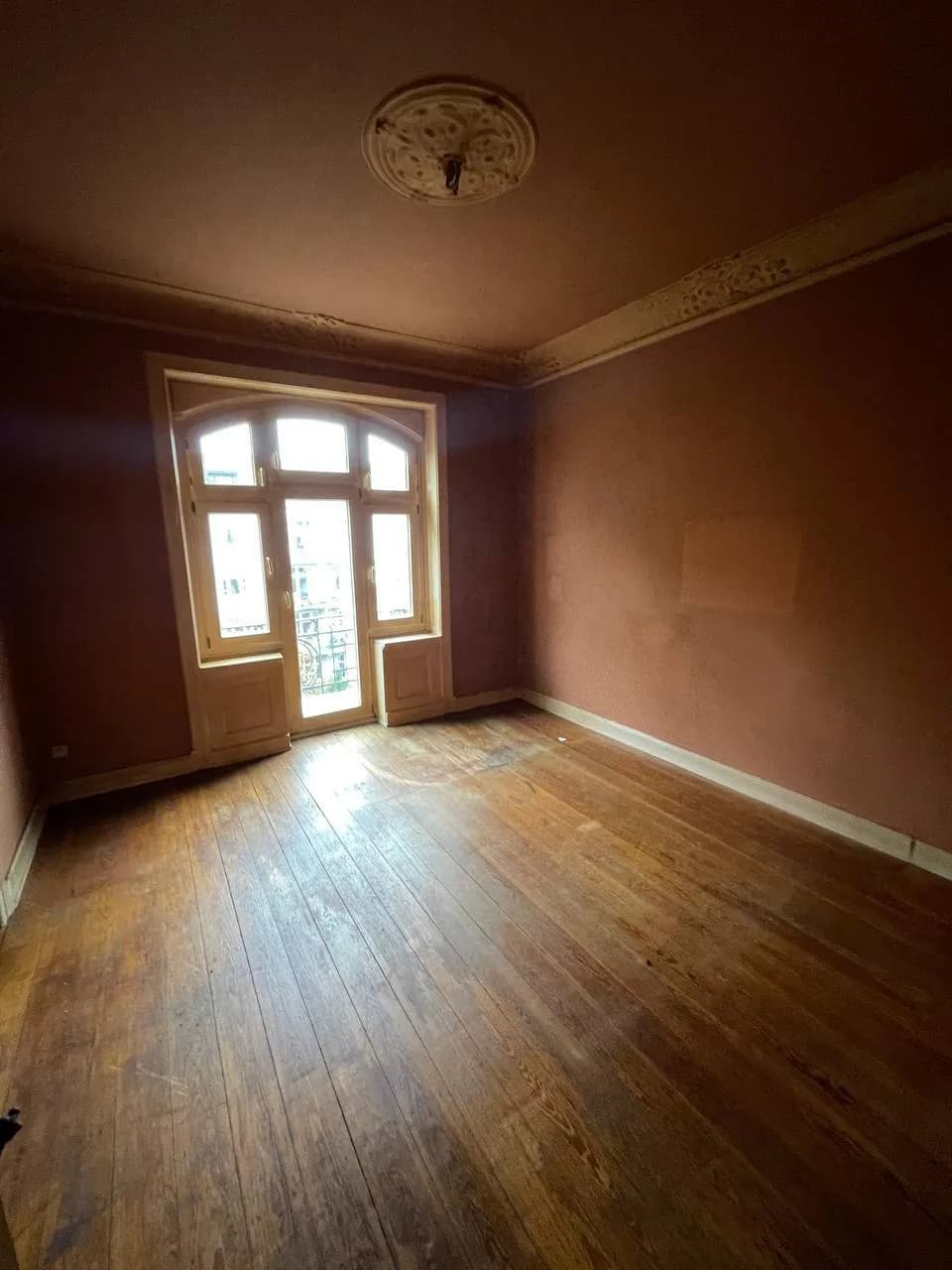 Leeres Zimmer mit Dielenboden, Stuckleisten und Rundbogen-Balkontür am Eppendorfer Weg nach der Wohnungsauflösung