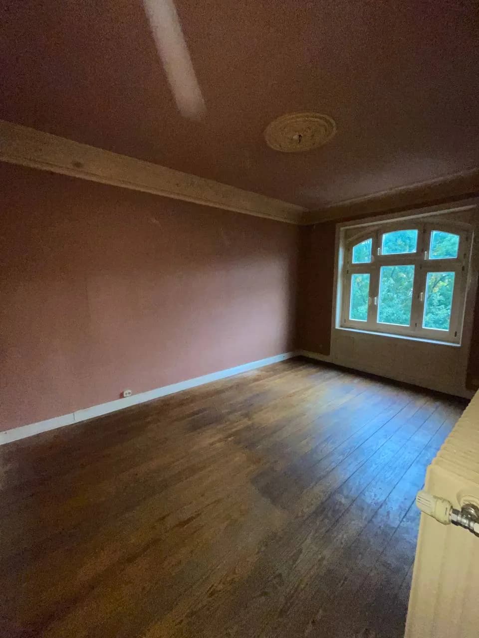 Leeres Zimmer mit Dielenboden, Stuckrosette und Rundbogenfenster am Eppendorfer Weg nach der Wohnungsauflösung