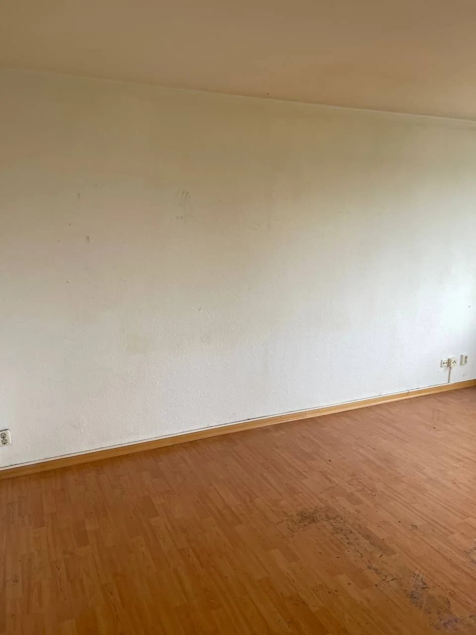 Geräumtes Zimmer in Wandsbek, leerer Laminatboden und weiße Wand