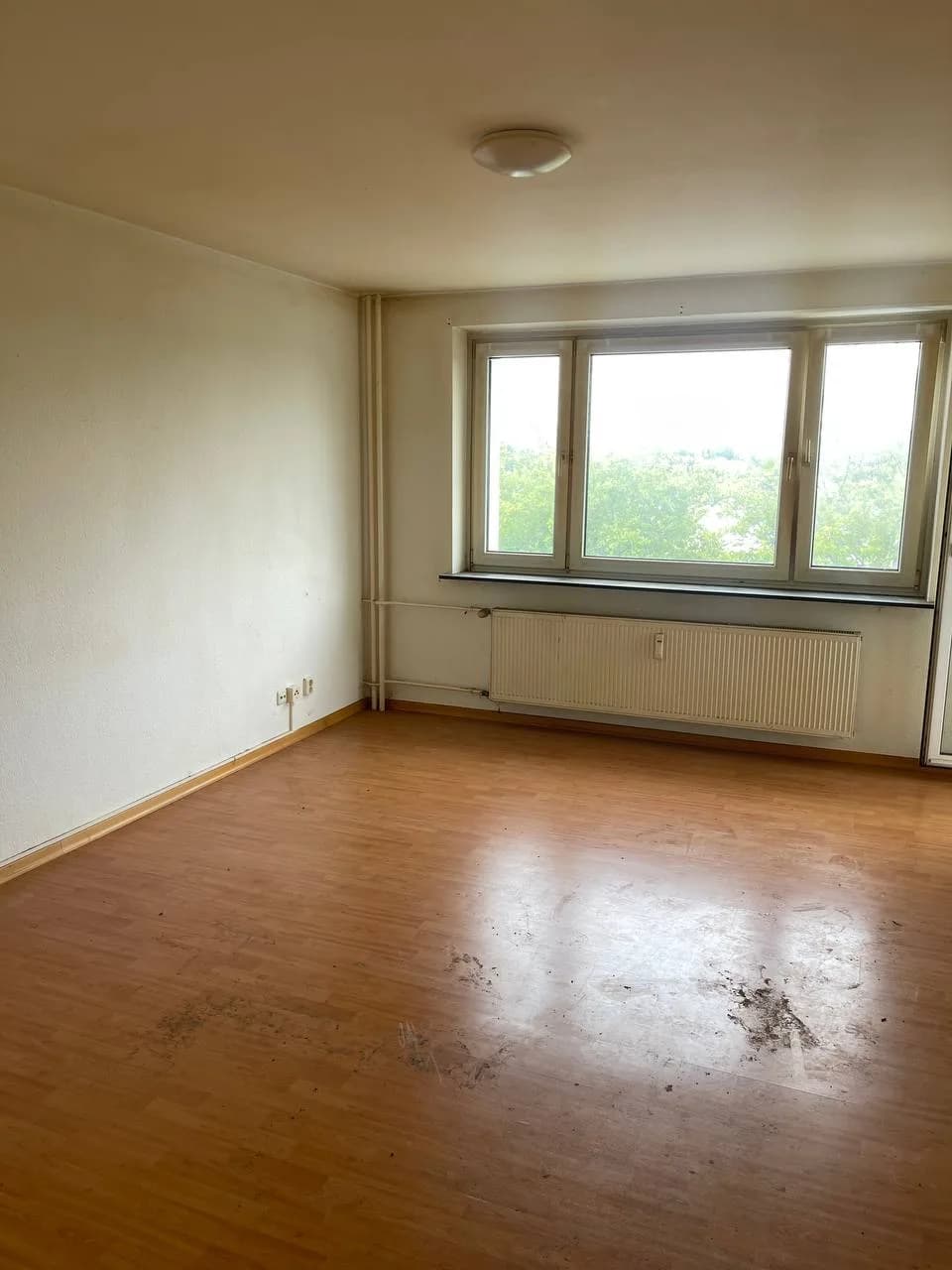 Dasselbe Zimmer in Wandsbek nach der Räumung, leerer Laminatboden vor dem Fenster