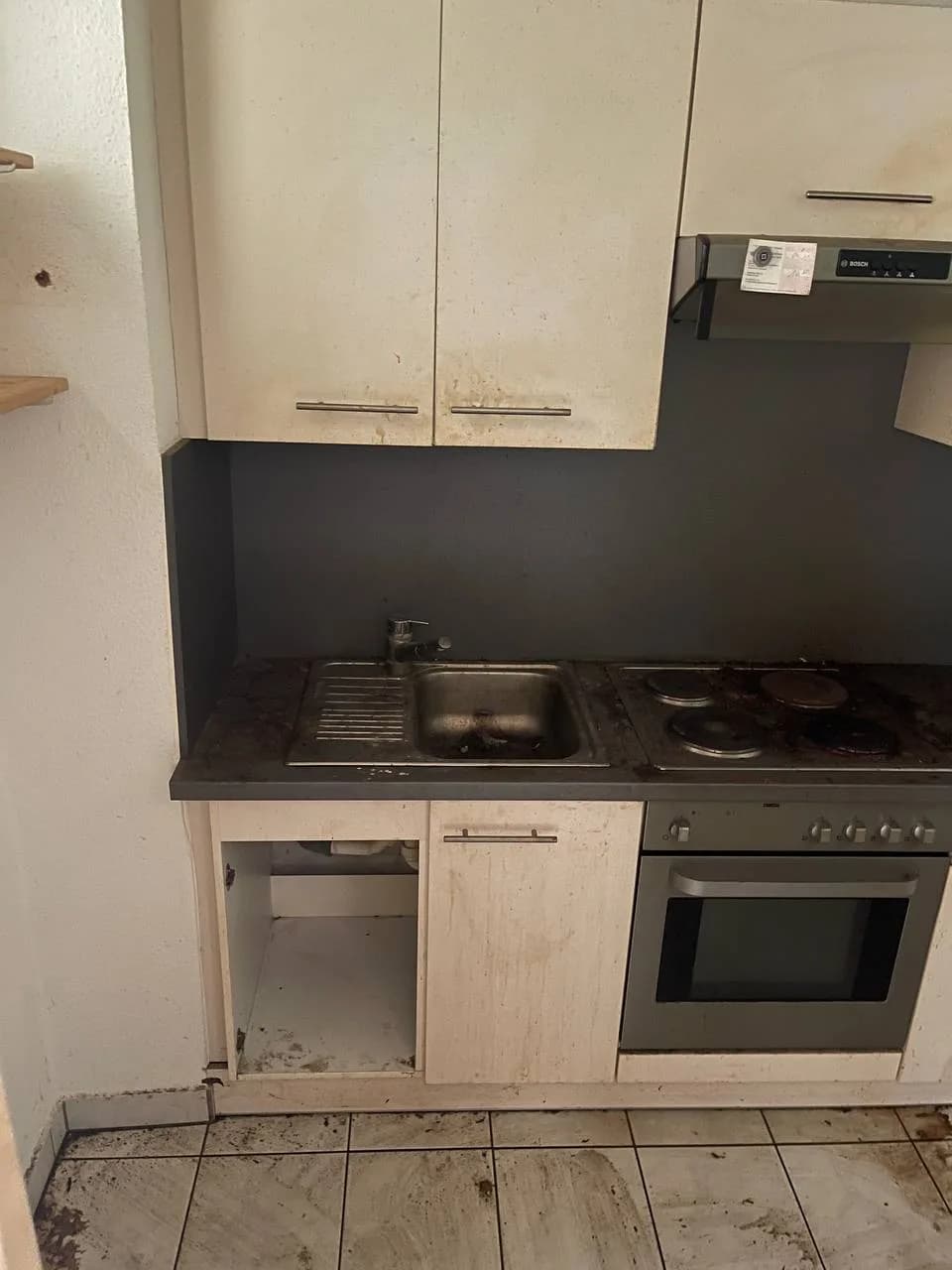 Leere Küche in Wandsbek nach der Räumung, Spüle und geöffneter Unterschrank sichtbar