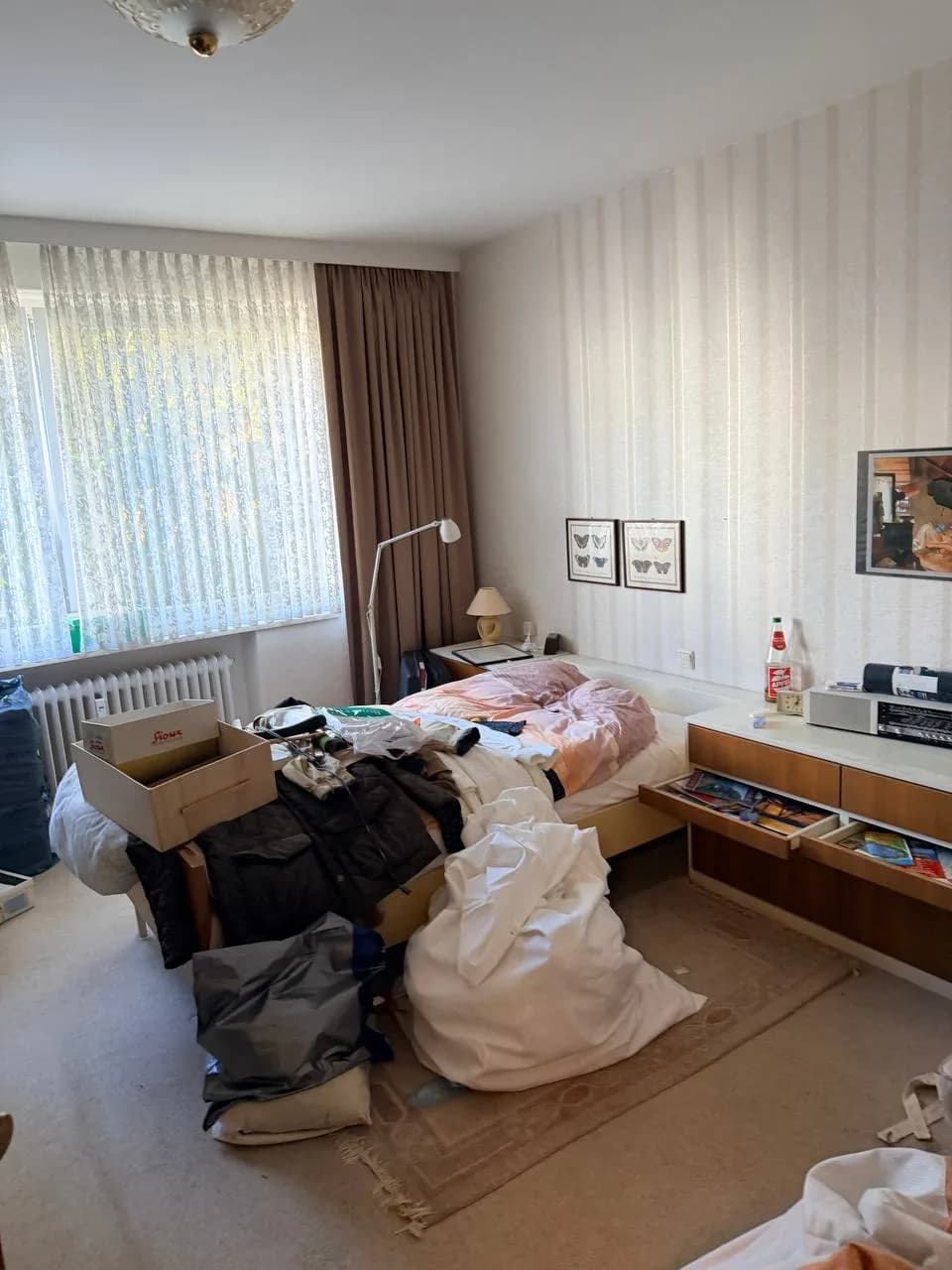 Schlafzimmer in Hamburg-Wandsbek vor der Räumung mit Bett, Kartons, Kleidung und Schmetterlingsbildern