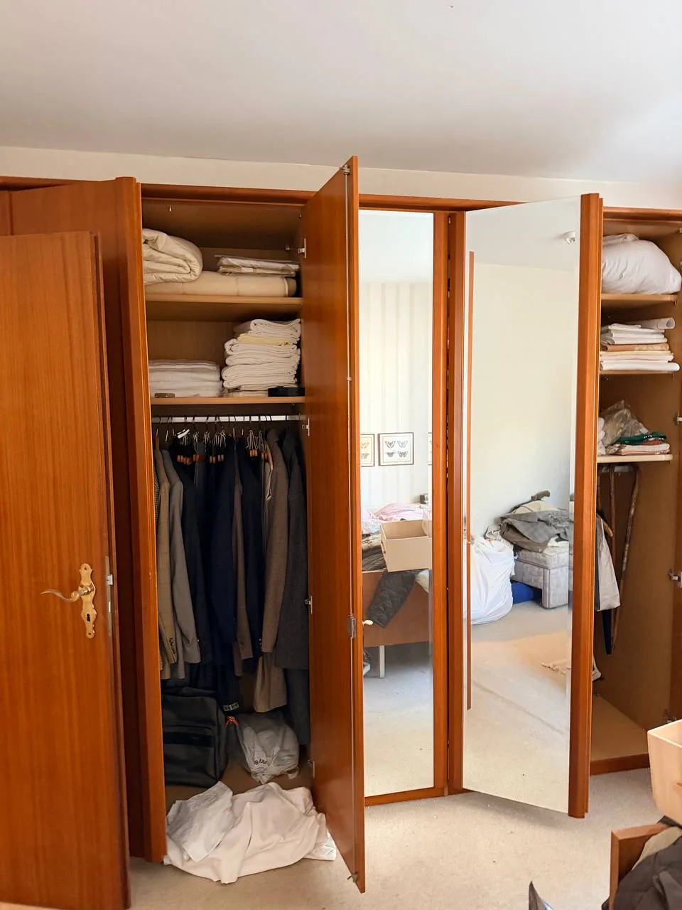Geöffneter Kleiderschrank mit Spiegeltüren, Anzügen und gefalteter Wäsche in Hamburg-Wandsbek