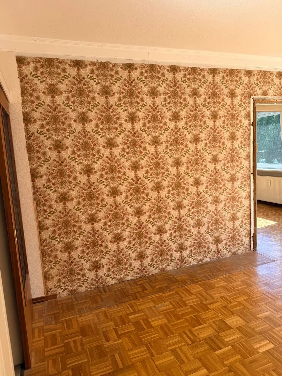 Freigelegte Blumentapete in Orange und Grün an einer Wand in Hamburg-Wandsbek nach der Räumung