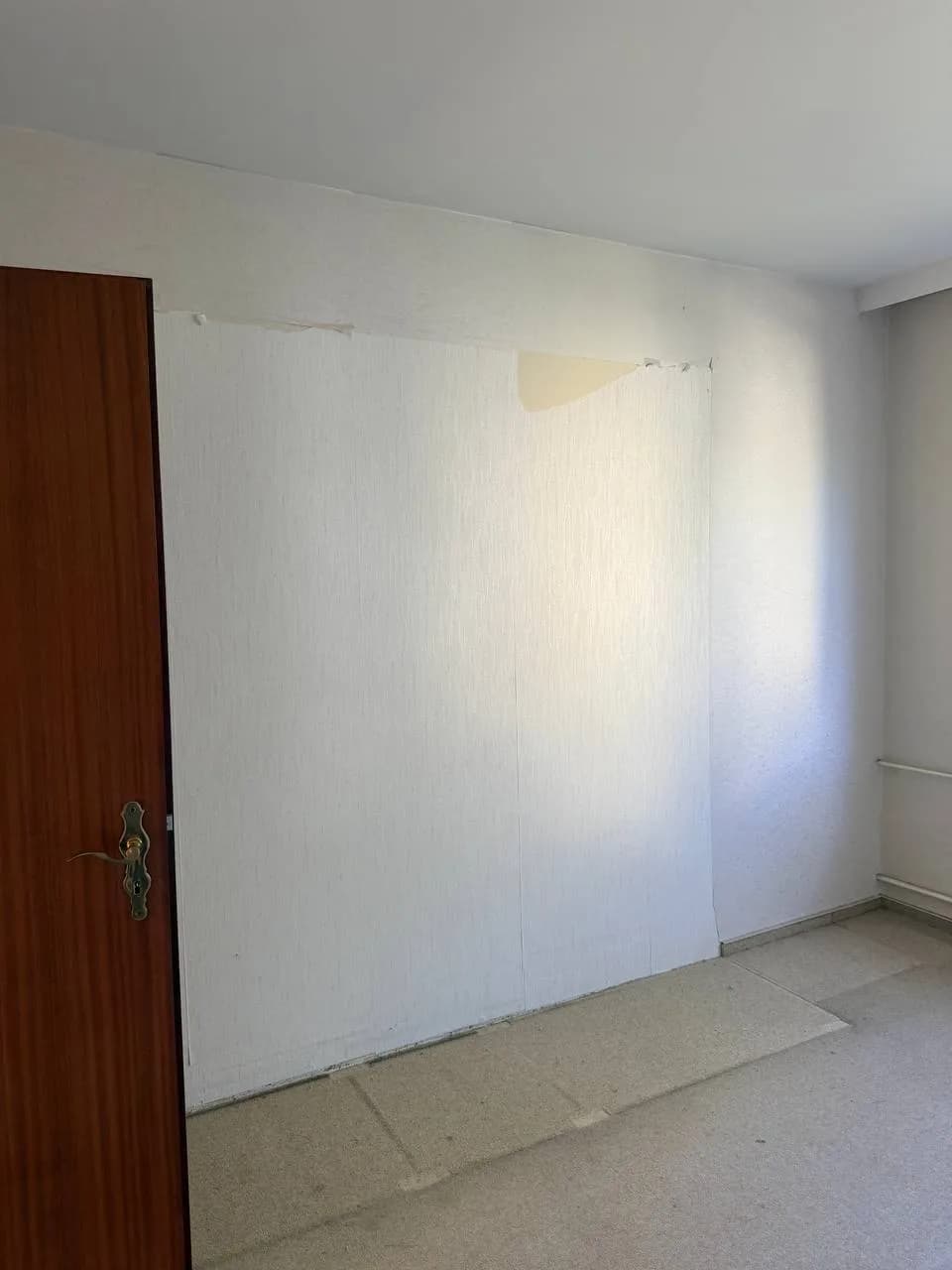 Helleres Tapetenfeld mit aufgerissener Ecke in einem leeren Zimmer in Hamburg-Wandsbek
