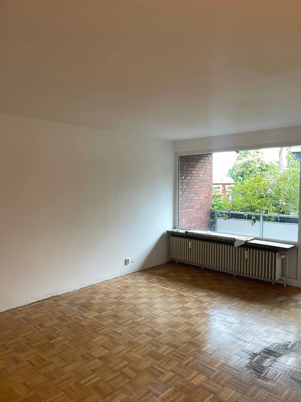 Leeres Zimmer in Wedel mit Fenster, Heizkörper und freigelegtem Stabparkett