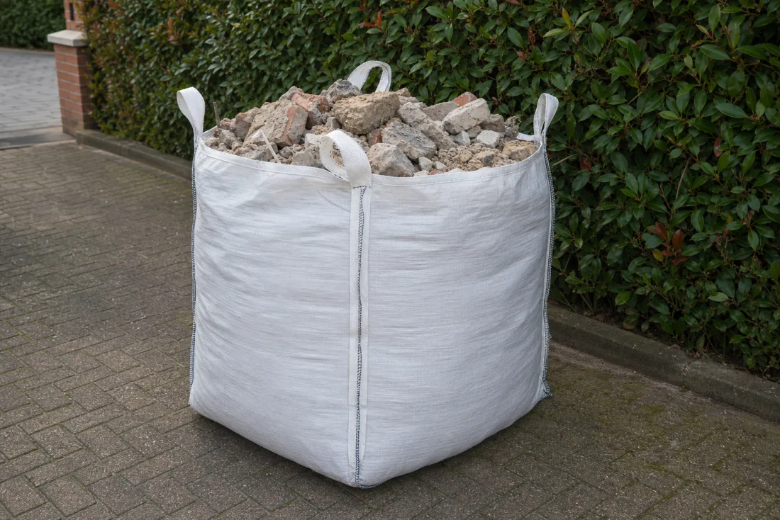 Weißer Big Bag gefüllt mit Bauschutt und Steinen, steht in einer Hamburger Einfahrt zur Abholung bereit