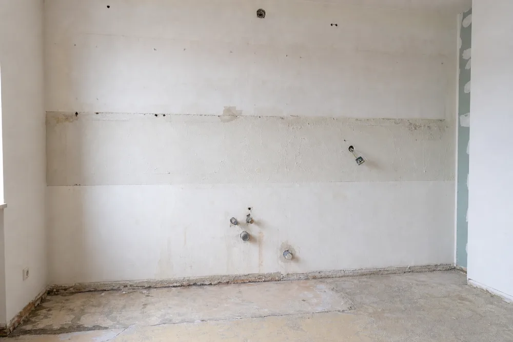 Leere Küchenwand nach dem Ausbau, nur Anschlüsse stehen noch vor