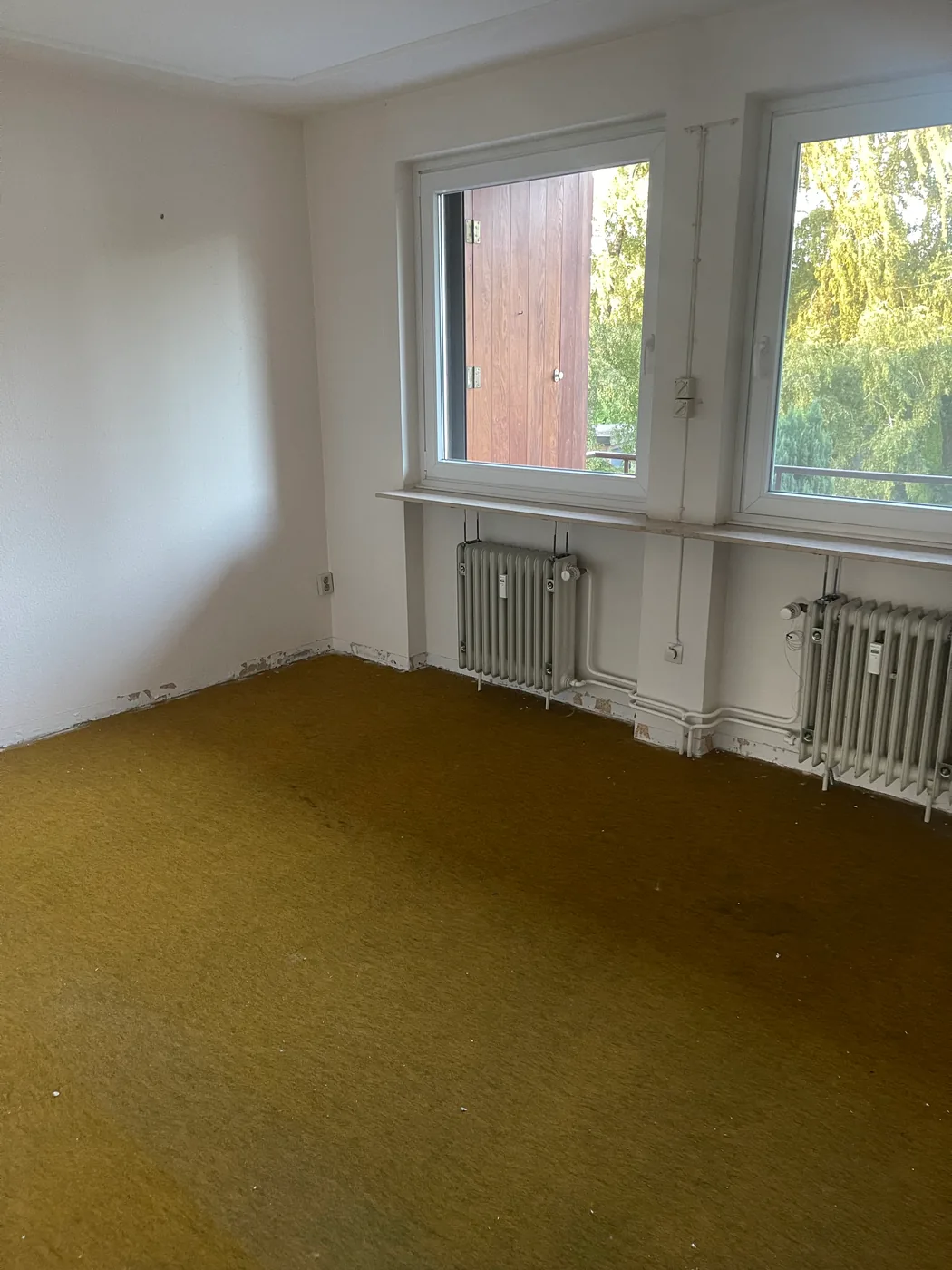 Leergeräumtes Zimmer in Hamburg-Berne mit altem senfgrünem Teppichboden vor dem Ausbau des Bodens