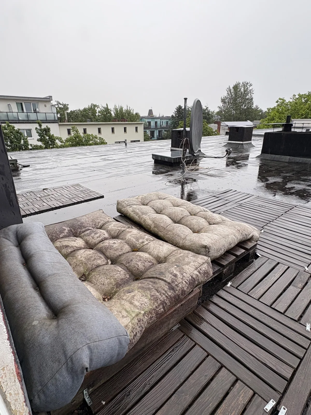 Vollgestellte Dachterrasse in Hamburg mit vermoosten Sitzauflagen auf einer Palette