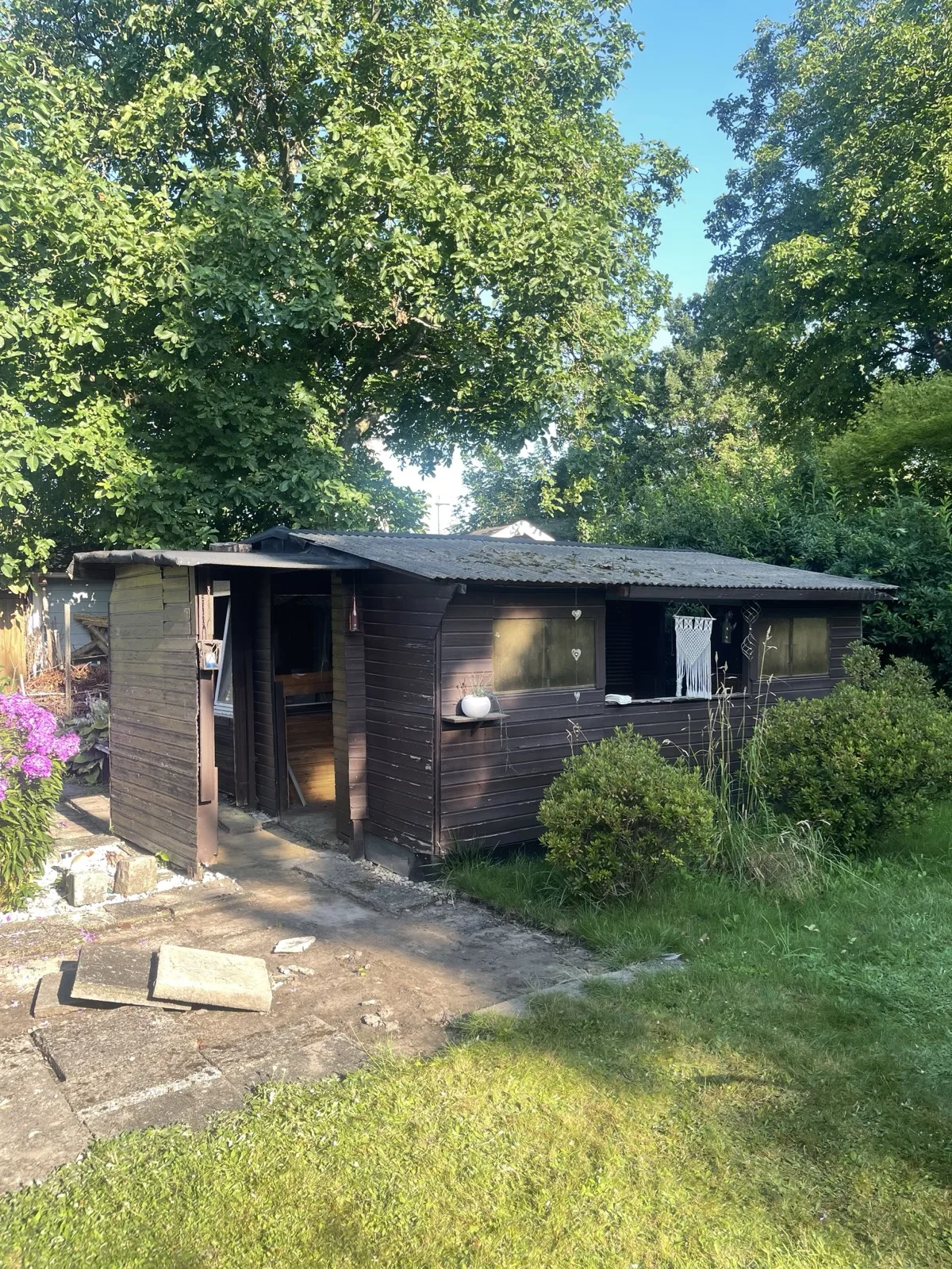 Alter Holzanbau an einer Gartenlaube in Hamburg vor dem Abriss, mit Fensterläden und Deko