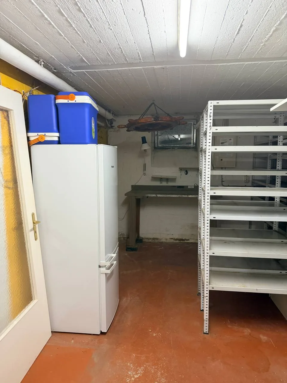 Dieselbe Werkstattecke nach der Räumung, freie Werkbank unter dem Kellerfenster, Steuerrad an der Decke