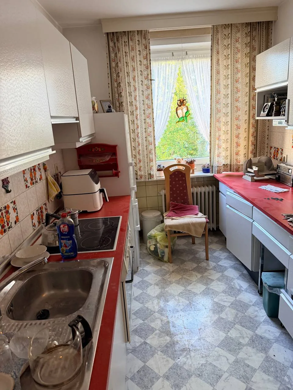 Küche mit roter Arbeitsplatte in Hamburg-Wandsbek vor der Wohnungsauflösung, mit Geräten und Geschirr