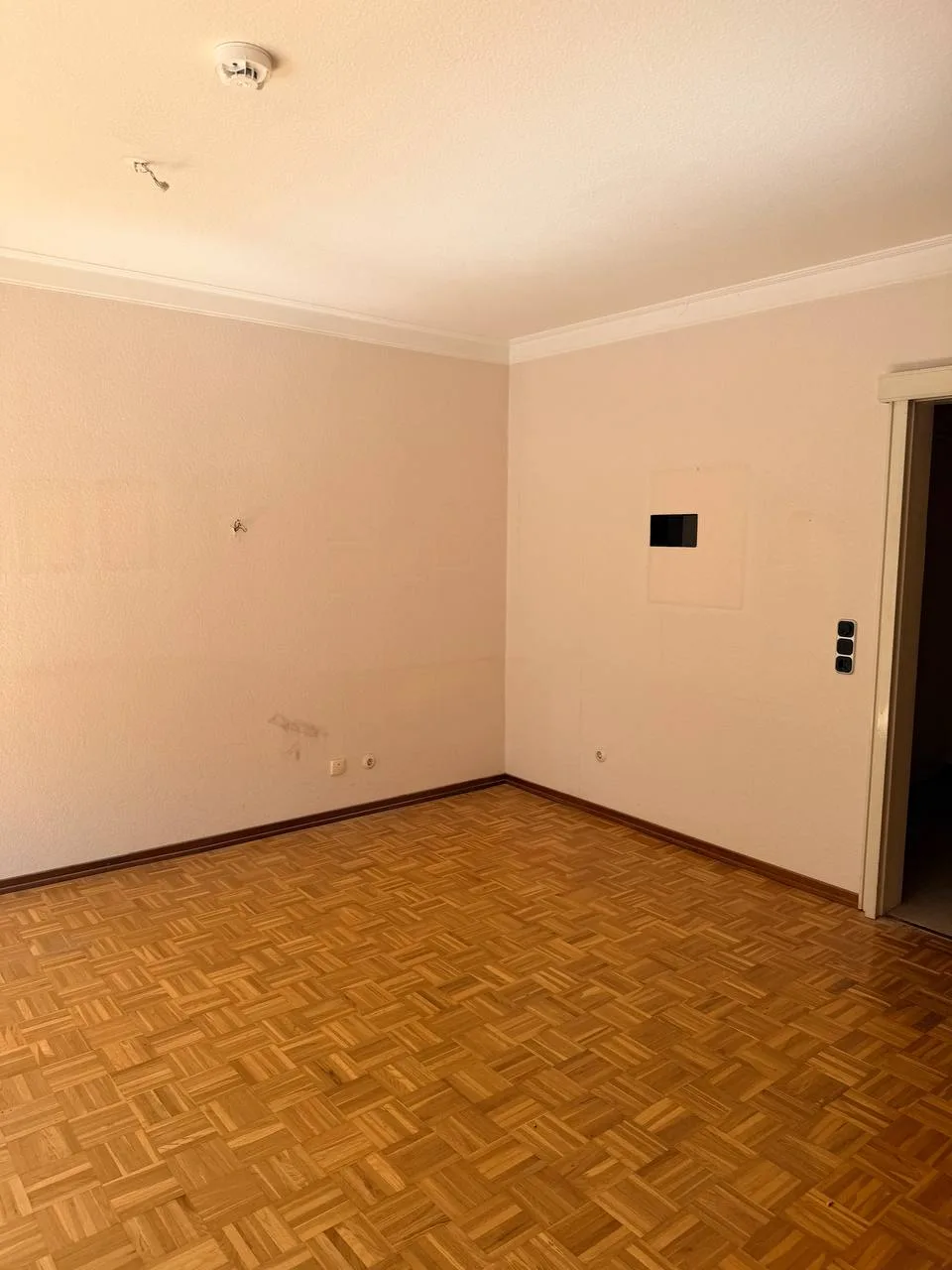 Leeres Zimmer mit Mosaikparkett und Durchgang in einer Wohnung in Hamburg-Wandsbek